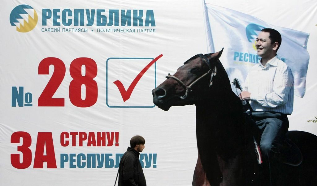 Мъж язди кон пред предизборен плакат в Бишкек