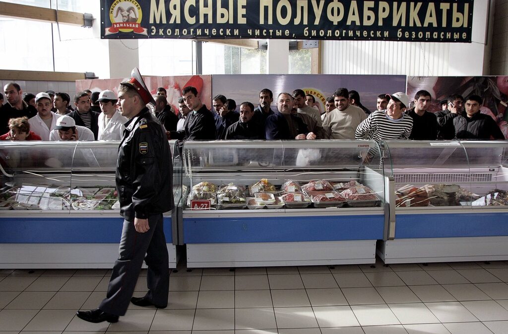 Полицай наблюдава лица с неславянски произход по време на акция на един от пазарите в Москва през 2006 г.