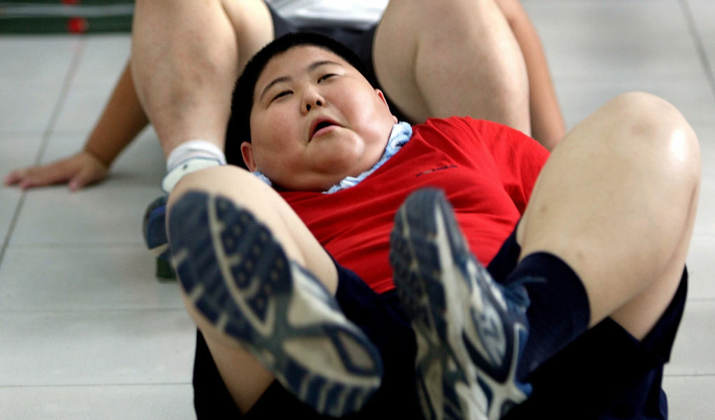 AN OVERWEIGHT CHINESE BOY DOES SIT-UPS DURING A WEIGHT REDUCTION CLASS IN BEIJING
