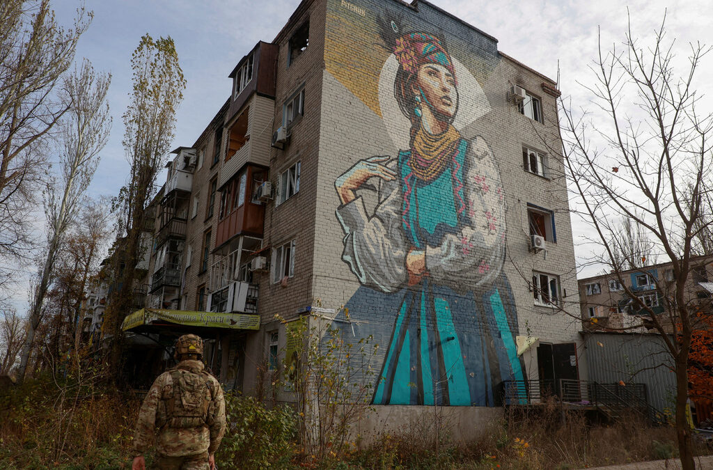 Украински военнослужещ върви до жилищна сграда, силно засегната от постоянните руски военни удари в град Авдиивка на фронтовата линия в Донецка област. 8 ноември 2023 г.
