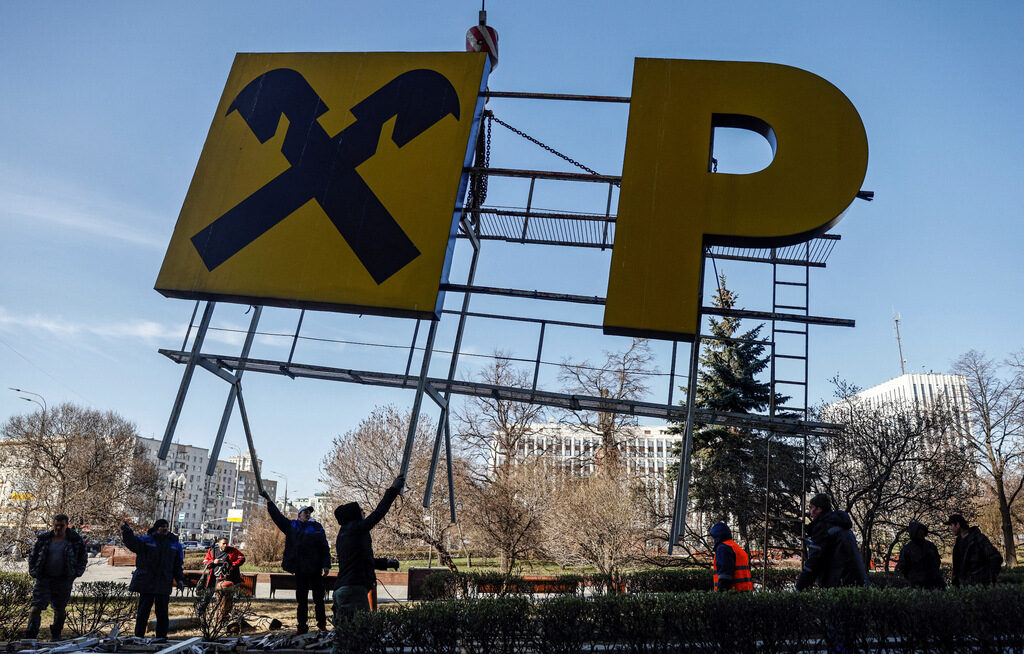 Работници демонтират рекламна конструкция на "Райфайзен" от сграда в Москва. 14 април 2023 г.