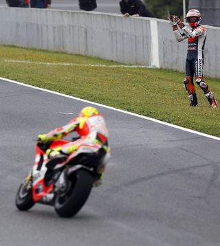 Honda's MotoGP rider Stoner applauds as Ducati's Rossi passes by, continuing in the race after the two riders crashed during the Spanish Grand Prix in Jerez