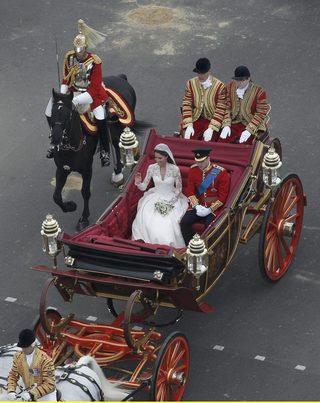 Britain's Prince William and Catherine, Duchess of Cambridge wave as they travel to Buckingham Palace in a 1902 State Landau along the Procession Route after their wedding in London