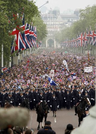 Police officers line in front of crowds of people as they wait for Britain's Prince William and his wife Catherine, Duchess of Cambridge, to appear at the balcony of the Buckingham Palace after their wedding in central London