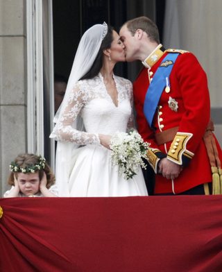 Britain's Prince William and his wife Catherine, Duchess of Cambridge, kiss as they stand next to bridesmaid Grace van Cutsem on the balcony at Buckingham Palace after their wedding in Westminster Abbey, in central London