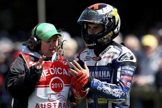 Yamaha MotoGP rider Lorenzo of Spain is assisted by medical personnel after crashing during the warm-up session of the Australian Grand Prix on Phillip Island