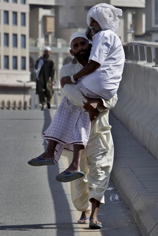 A Muslim pilgrim carries an older pilgrim during the annual haj pilgrimage outside the Grand Mosque in Mecca