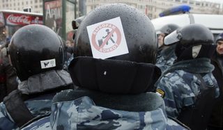 A police officer with a sticker attached to his helmet by a protester observes an opposition rally in Moscow