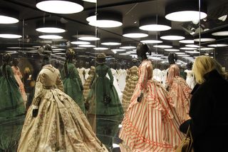 A visitor looks at dresses during the press presentation of the 'Louis Vuitton - Marc Jacobs: The Exhibition' at the Museem of Decorative Arts in Paris