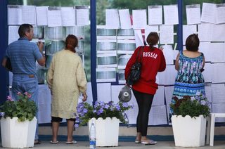 People look through lists with information, left by local residents to be found by their acquaintances, after floods in the town of Krymsk