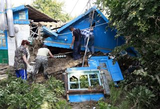 Local residents work amidst the debris of a house, damaged by floods, in the town of Krymsk in Krasnodar region