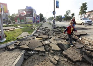 Local residents walk along a street, damaged by floods, in the town of Krymsk in Krasnodar region