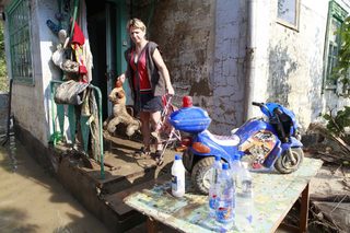 A local resident brings her wet toys outside her house that has damaged by floods in the town of Krymsk