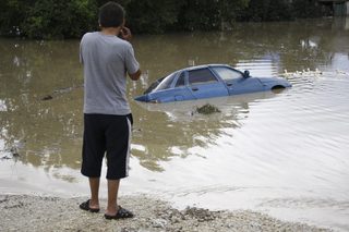 A local resident looks at a submerged car in a flooded street in the village of Novoukrainsk