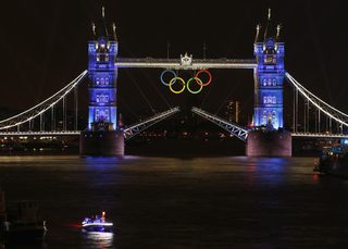 The Olympic rings hang on London's Tower Bridge as a speedboat driven by Britain's David Beckham and carrying the Olympic torch prepares to mark the opening ceremony of the 2012 Olympic Games