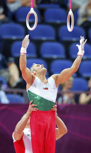Jordan Jovtchev of Bulgaria is helped to the rings before competing during the men's gymnastics qualification in London
