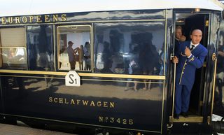 A car attendant gestures from the Orient Express as the luxury train arrives at the main railway station in Bucharest