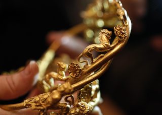 Museum official displays a golden a tiara with animal motifs, part of a recently unearthed discovery from an ancient Thracian tomb, at the Archaeology Museum in Sofia