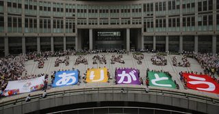 A message reading "THANK YOU" made up by people sitting in formation and banners reading "Arigato" are displayed during an event celebrating Tokyo being chosen to host the 2020 Olympic Games, in Tokyo