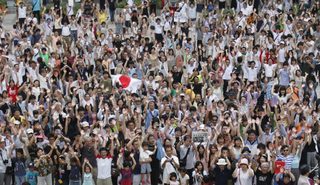 People raise their hands as they shout "banzai" or cheers, during an event celebrating Tokyo being chosen to host the 2020 Olympic Games, at Tokyo Metropolitan Government Building