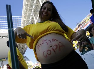 A pregnant woman points to her belly as she attends the opening ceremony of the 2014 World Cup at the Corinthians arena in Sao Paulo