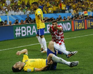 Brazil's Oscar lies on ground after he was fouled by Croatia's Vrsaljko as Brazil's Alves looks on during their 2014 World Cup opening match at the Corinthians arena in Sao Paulo