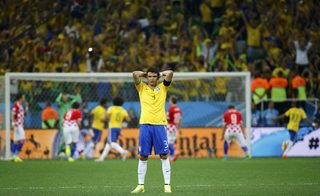 Brazil's Silva turns his back as teammate Neymar scores a goal against Croatia during a penalty at their 2014 World Cup opening match at the Corinthians arena in Sao Paulo
