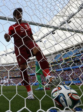 Portugal's Coentrao picks up the ball after a goal by Germany's Mueller during their 2014 World Cup Group G soccer match at the Fonte Nova arena in Salvador