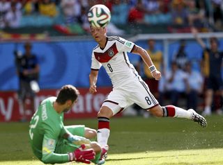 Portugal's goalkeeper Patricio falls on the ground as he fights for the ball with Germany's Ozil during their 2014 World Cup Group G soccer match at the Fonte Nova arena in Salvador