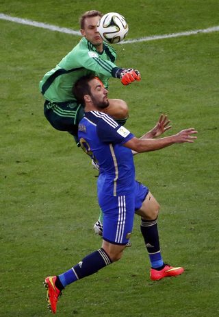 Germany's goalkeeper Manuel Neuer collides with Argentina's Gonzalo Higuain as he punches the ball away during their 2014 World Cup final at the Maracana stadium in Rio de Janeiro