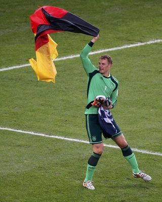 Germany's goalkeeper Manuel Neuer celebrates with his national flag after winning their 2014 World Cup final against Argentina at the Maracana stadium in Rio de Janeiro