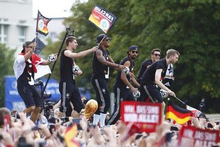 Germany's national soccer team players wave from an open-top bus during a celebration parade in Berlin