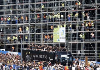 Construction workers take pictures as Germany's 2014 Brazil World Cup squad proceed in an open-top bus through the capital during a parade to mark the team's victory