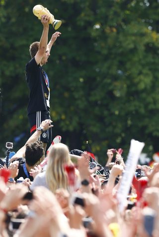 German soccer team captain Lahm lifts lifts up the World Cup trophy on a stage during celebrations to mark the team's 2014 Brazil World Cup victory, at a 'fan mile' public viewing zone in Berlin