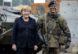 German Chancellor Merkel poses with a German soldier for a family photo during her visit at the German army Bundeswehr training ground in Munster