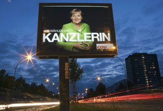 File photo of cars driving past an election poster of German Chancellor and leader of the CDU Merkel in Berlin
