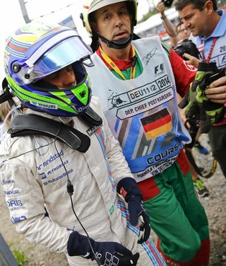 Williams Formula One driver Massa of Brazil walks off the track after crashing with his car in the first corner after the start of the German F1 Grand Prix at the Hockenheim racing circuit