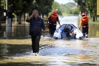 A fire-fighter reacts as he walks on a flooded street in the town of Mizia