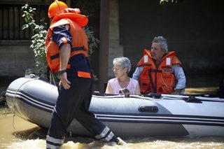 A woman and a man sit inside a boat as they are rescued during floods in the town of Mizia