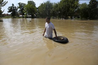 A man carries a tire on a flooded street in the town of Mizia
