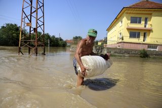 A man carries his belongings on a flooded street in the town of Mizia