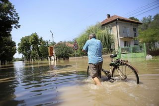 A man pushes his bicycle through a flooded street in the town of Mizia