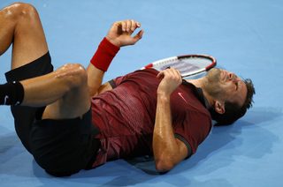 Grigori Dimitrov of Bulgaria lies on the court after he fell during his match against Roger Federer of Switzerland at the Swiss Indoors ATP tennis tournament in Basel