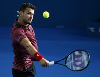Dimitrov of Bulgaria plays a backhand return to Federer of Switzerland during their men's singles semi final at the Brisbane International tennis tournament in Brisbane