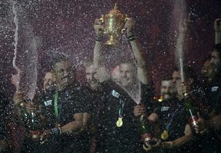 Richie McCaw of New Zealand holds the Webb Ellis Cup as he celebrates with teammates after beating Australia to win the Rugby World Cup final match at Twickenham in London