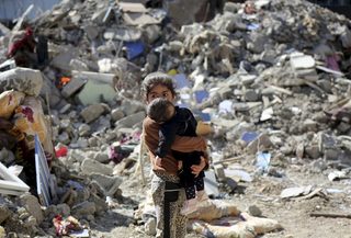 A girl carries a baby as she walks in the debris of buildings, which were damaged during the security operations and clashes between Turkish security forces and Kurdish militants, in the southeastern town of Cizre in Sirnak province
