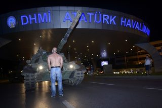 A man stands in front of a Turkish army tank at Ataturk airport in Istanbul