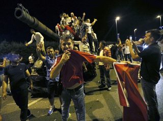 People stand on a Turkish army tank at Ataturk airport in Istanbul