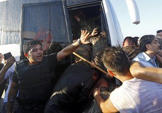 A policeman protects soldiers from the mob after troops involved in the coup surrendered on the Bosphorus Bridge in Istanbul