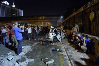 A crowd gathers near a wrecked police vehicle at military headquarters in Ankara